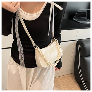 White crescent crossbody bag with thick chain detail shown on a fashion model