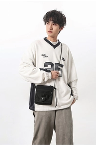 Front view of black functional crossbody bag with mesh pocket shown on a male model