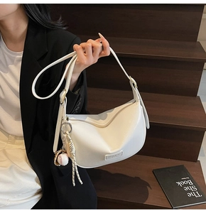 Détail du sac hobo blanc à motif litchi avec fermeture éclair et breloque de baseball