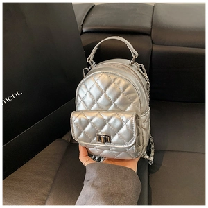 Detail of silver quilted backpack featuring metallic finish and elegant chain strap
