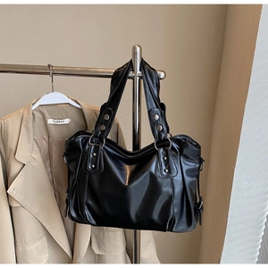Close-up of black PU leather tote bag with wide strap and silver metal rivet details