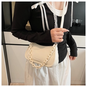 Detail of a minimalist off-white saddle bag with matte PU leather and thick chain strap