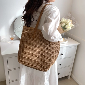 Détail d'un sac cabas tissé avec bandoulières en cuir marron et coutures renforcées de qualité