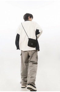 Back view of a black functional crossbody bag on model with street style outfit