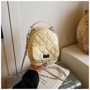 Detail of beige quilted mini backpack with metal chain straps and twist-lock closure