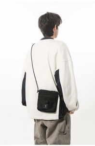 Detail of a black nylon crossbody bag featuring a front mesh pocket on a model