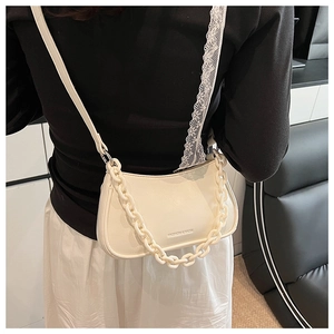 Close-up of a white hobo bag with thick plastic chain detail and fashion logo on the leather