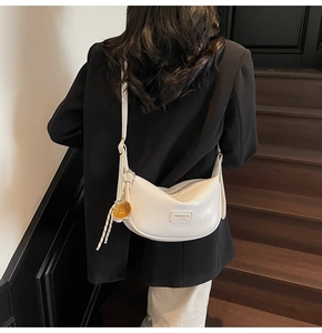 Sac à bandoulière demi-lune blanc minimaliste sur mannequin avec pendentif balle de sport