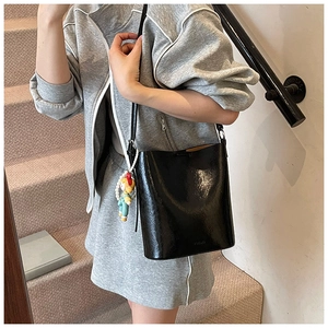 Glossy black bucket bag detail with elegant pearl and cartoon girl pendant accessory