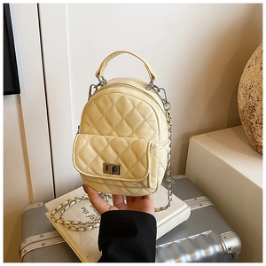 Detail of beige quilted backpack with silver chain strap and metal turn-lock pocket