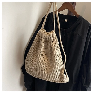 Close-up of beige crochet woven bucket bag with drawstring closure and fine texture