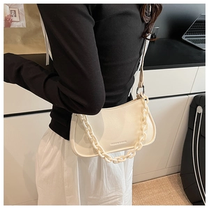 Detail view of cream dumpling bag with thick chain strap worn over the shoulder