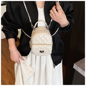 Detail of cream-colored quilted patent leather mini backpack with gold-tone chain straps