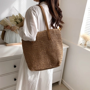 Détail d'un sac cabas en paille tissée avec bandoulière en cuir brun, style bohème