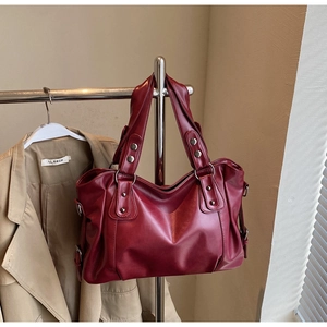 Detail view of large dark red leather tote bag with metallic studs and side buckles