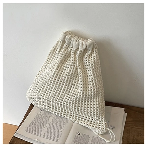 Detailed close-up of hollow crochet texture and drawstring on beige knit bucket bag