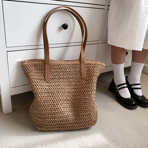 Vue détaillée de la texture du sac cabas en paille tissée et des anses en cuir marron