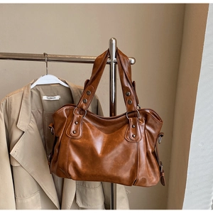 Macro shot of retro brown leather tote bag with metallic studs and zip closure detail