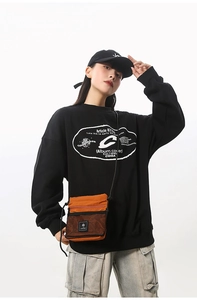 Detail of trendy orange mesh crossbody bag paired with black streetwear sweatshirt