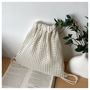 Detail of cream crochet drawstring backpack with woven texture and artistic side ropes