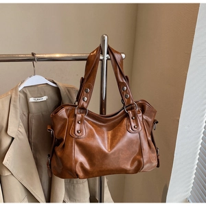 Detail of caramel brown PU leather tote bag with silver studs and metal ring accents