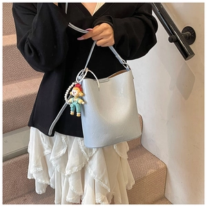 Detail of light blue bucket bag with natural PU leather texture and pearl doll charm
