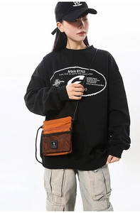 Detail of orange techwear crossbody bag with black mesh pocket and adjustable cord strap