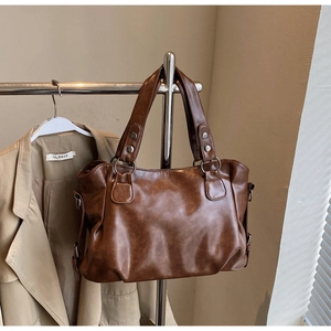 Close-up of vintage brown leather tote bag with sturdy handles and silver hardware detail