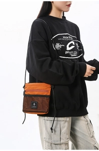 Close-up of durable orange nylon crossbody bag with black mesh pocket and logo