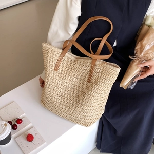 Détail du sac cabas en paille tissée avec bandoulière en similicuir brun et surpiqûres