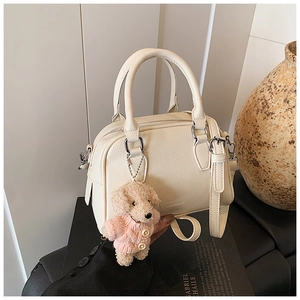 Detail of cream Boston bag with pebble texture, silver hardware and a cute puppy charm