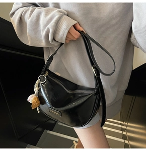 Vue détaillée du sac hobo noir brillant avec accessoire de charme gant de baseball