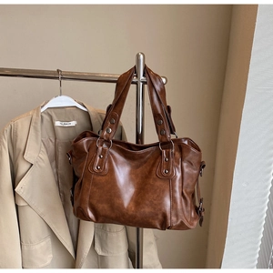 Detail of vintage brown tote bag showing supple faux leather texture and metal ring hardware