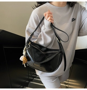 Détail du sac hobo noir brillant avec charm de baseball et logo métallique chic
