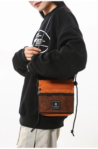 Model wearing a vibrant orange nylon crossbody bag with black mesh pocket and shoulder strap