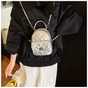 Close-up of silver quilted mini backpack featuring metallic finish and chain strap details