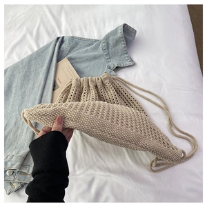 Detail of beige crochet knit drawstring backpack showing hollow texture and cotton material
