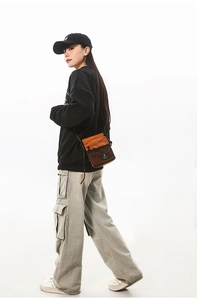 Side view of a person wearing an orange nylon crossbody bag with black mesh pocket detail