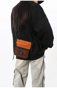 Detail of orange nylon crossbody bag with honeycomb mesh pocket and black cord strap