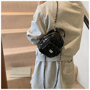 Detail of black quilted patent leather mini backpack with silver metal chain straps