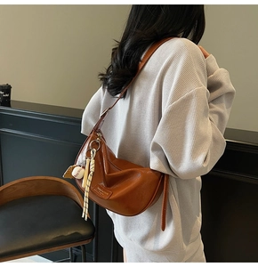 Vue détaillée du sac bandoulière marron en similicuir avec pendentif de baseball