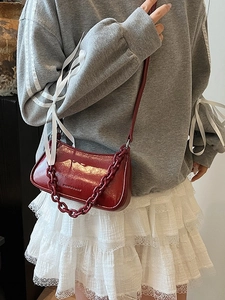 Glossy burgundy chain dumpling bag shown on model with trendy shoulder strap styling