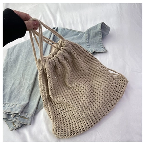 Detailed close-up of beige crochet hollow-out pattern and drawstring on the bucket bag