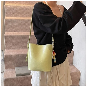 Detail of light green bucket bag with wrinkled texture, logo and pearl doll charm