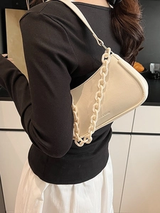 Chic cream dumpling bag with chunky chain detail and shoulder strap in minimalist style