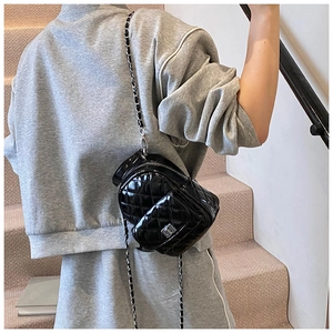 Detail of black patent leather quilted mini bag with silver chain strap and metal lock