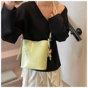 Close-up of pistachio green bucket bag with wrinkled texture and pearl doll charm