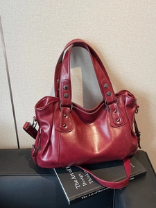 Retro burgundy large capacity tote bag with rivets and adjustable strap on a sofa