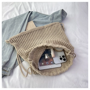Detail of hollow knit drawstring bag showing interior space for tablet and essentials