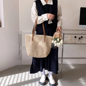 Sac cabas tissé beige chic avec anses en cuir marron porté par un mannequin en décor